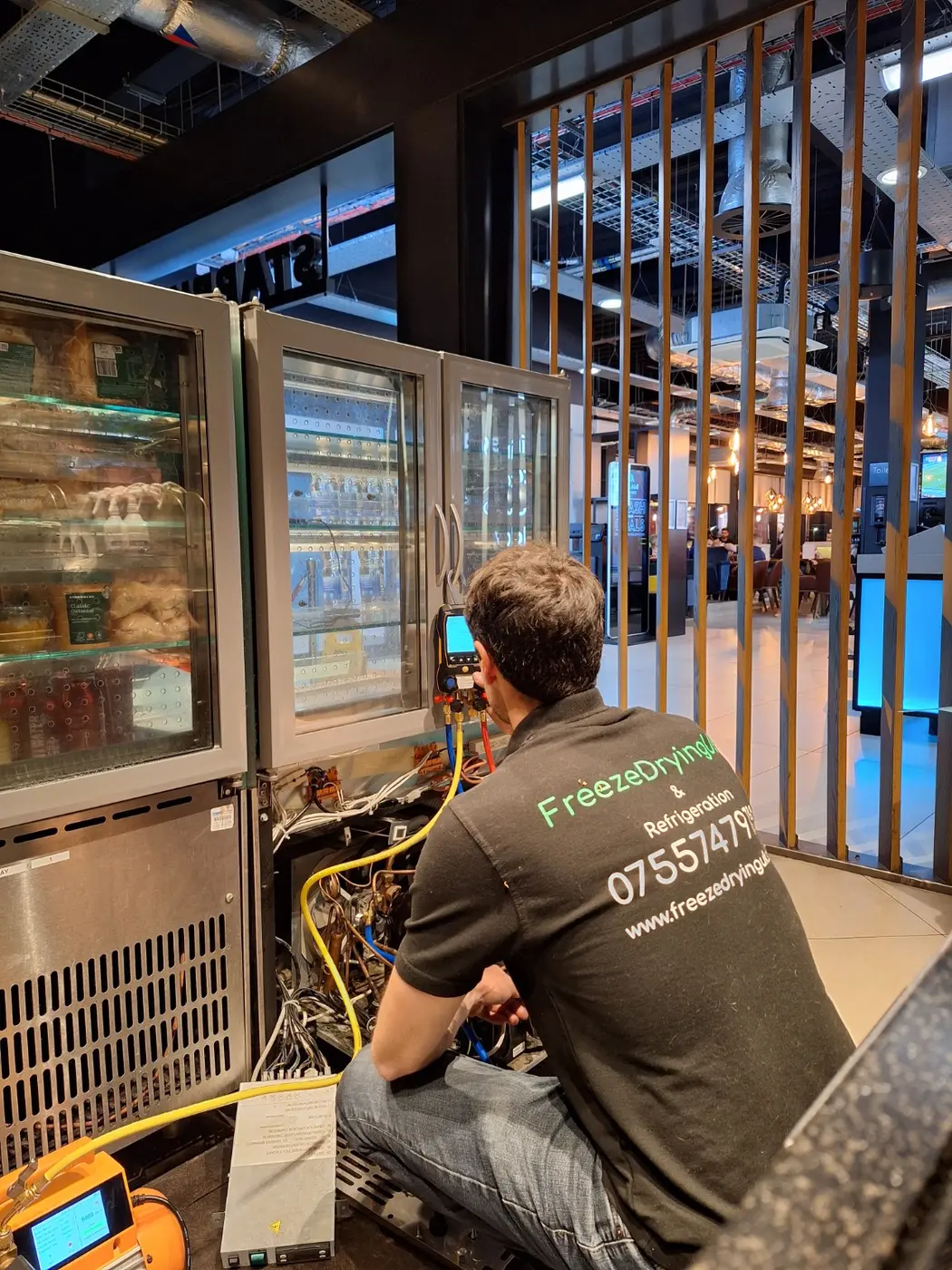 Refrigeration engineer diagnosing a commercial display cabinet